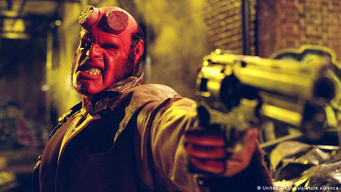 Hellboy, mit rotem Gesicht, hat die Pistole erhoben. 