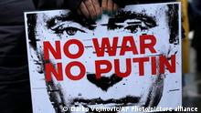 A woman holds a banner during a protest against the Russian invasion and in solidarity with the Ukrainian people, in Belgrade, Serbia, Saturday, Dec. 24, 2022. (AP Photo/Darko Vojinovic)