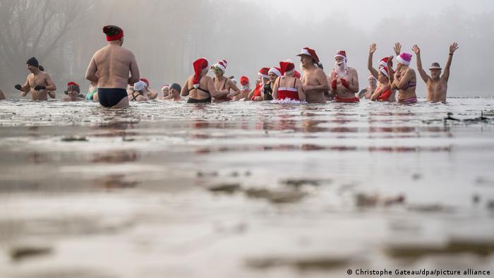 Miembros de la asociación Focas de Berlín se bañan entre trozos de hielo durante el tradicional baño de Navidad en el lago Orankesee, en Berlín.