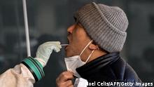 A health worker takes a swab sample from a man to be tested for the Covid-19 coronavirus at a hospital in Beijing on December 26, 2022. (Photo by Noel CELIS / AFP) (Photo by NOEL CELIS/AFP via Getty Images)