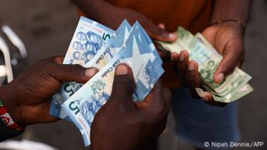 Hands holding cedi banknotes