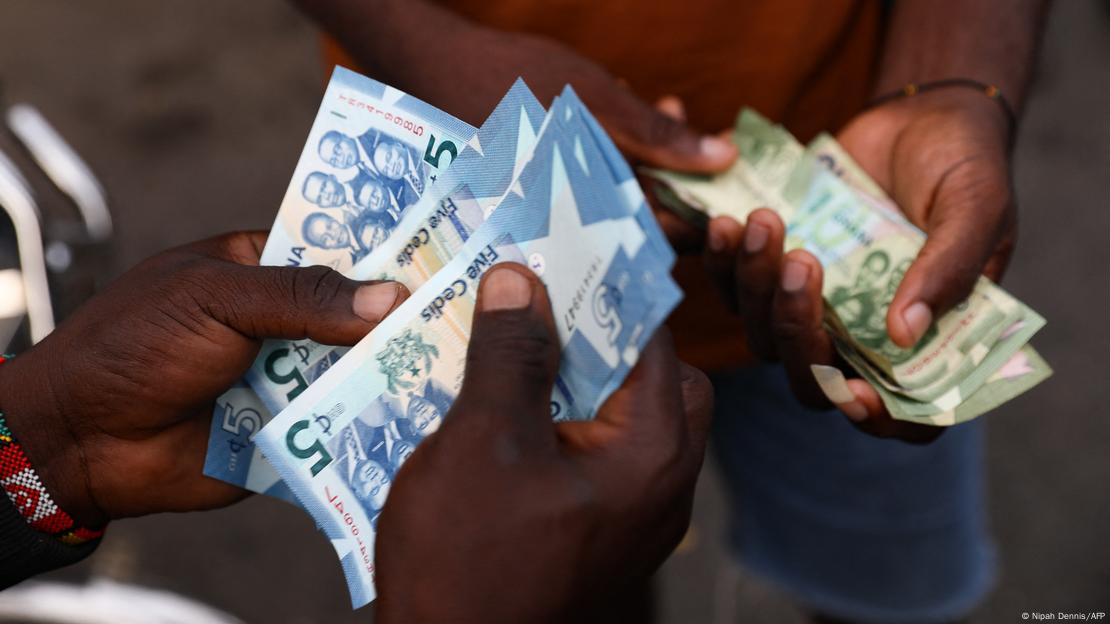 Des hommes s'échangent des cédis au marché d'Accra Des hommes s'échangent des cédis au marché d'Accra