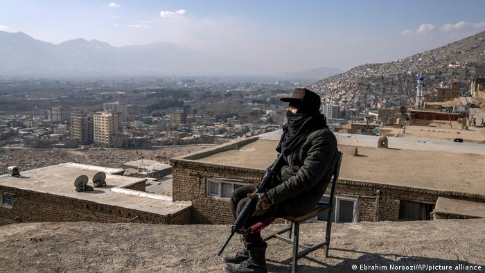 Sitzender Taliban-Kämpfer betrachtet von erhöhtem Standort aus die Stadt Kabul 
