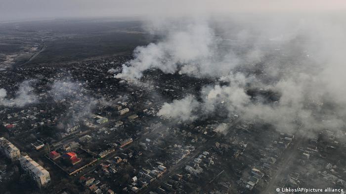 Amplia vista aérea de una ciudad en penumbra. Numerosos edificios despiden un denso humo.