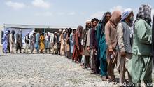 28.7.2022, Kabul, Afghanistan, Afghan internally displaced refugee men stand in a queue to identify themselves and get cash as they return home to the east, at the United Nations High Commissioner for Refugees (UNHCR) camp in the outskirts of Kabul on July 28, 2022. - Hundreds of internally displaced Afghans who had taken refuge in the capital left for their homes in the country's eastern provinces Thursday, almost a year after the war that forced them to flee ended. (Photo by Wakil KOHSAR / AFP) (Photo by WAKIL KOHSAR/AFP via Getty Images)