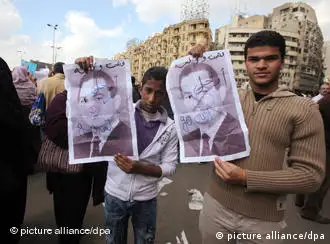 Protesters holding pictures of Mubarak with an X over his face