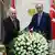  Recep Tayyip Erdogan and MHP head Devlet Bahceli, two men in a room shake hands, flower bouquet in the foreground, flags behind them.
