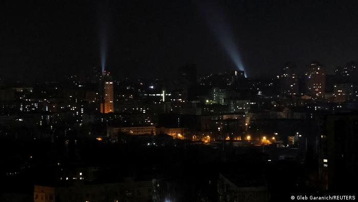 Sobre los tejados de la ciudad se ven dos haces de luz enfocados hacia el cielo.