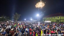 Fireworks light up the sky as people react while they celebrate after counting down to the new year at Miracle Center Cathedral in Kampala, Uganda, on January 1, 2023. (Photo by BADRU KATUMBA / AFP)