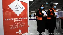 Zwei Flughafenmitarbeiterinnen warten auf Passagiere aus China vor einem Coronavirus-Testbereich auf dem Flughafen Roissy Charles de Gaulle. Angesichts der aktuellen Corona-Infektionswelle in China führt Frankreich wie einige andere Länder auch eine Testpflicht für Reisende aus dem Land ein. +++ dpa-Bildfunk +++