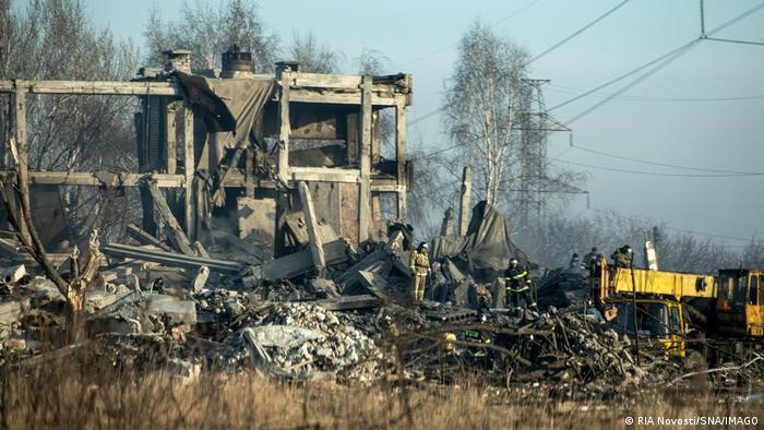 Zerstörte Gebäudeteile vor Bäumen und blauem Himmel in der Ostukraine