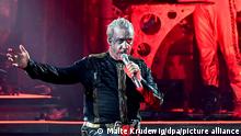 Rammstein's frontman, Till Lindemann, performing on stage with silver make up.