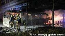 01.01.2023, Berlin: Feuerwehrmänner löschen an der Sonnenallee einen Reisebus, der von Unbekannten angezündet worden war. Foto: Paul Zinken/dpa +++ dpa-Bildfunk +++