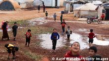 TOPSHOT - Chilrden play around water puddles after heavy rain, at the Kafr Arouk displacement camp in the rebel-held northern countryside of Syria's Idlib province, on November 25, 2022. (Photo by Aaref WATAD / AFP) (Photo by AAREF WATAD/AFP via Getty Images)