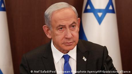 Ministerpräsident Benjamin Netanjahu schaut ernst vor israelischer Flagge