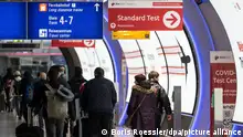 06.01.2023, Hessen, Frankfurt/Main: Passagiere gehen an einem Corona-Testzentrum am Flughafen Frankfurt vorbei. Aus China ankommende Passagiere sollen künftig stichprobenmäßig auf Corona getestet werden. Foto: Boris Roessler/dpa +++ dpa-Bildfunk +++