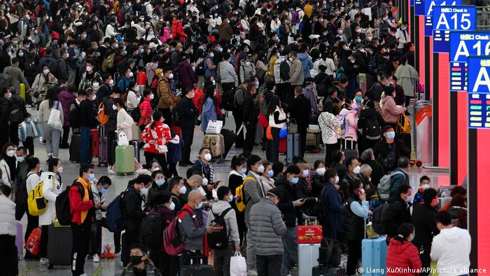 Cientos de personas con mascarillas y equipaje se preparan para coger sus trenes en la estación de ferrocarril del Norte de Shenzhen, en la provincia meridional china de Guangdong. 