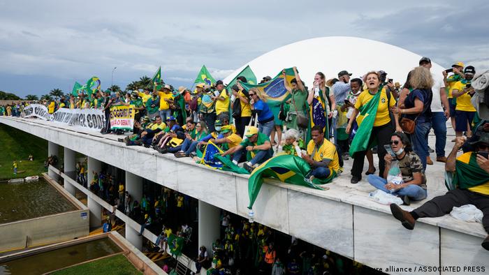 Demonstranten mit Brasilienfahnen sitzen auf dem Dach des Kongressgebäudes