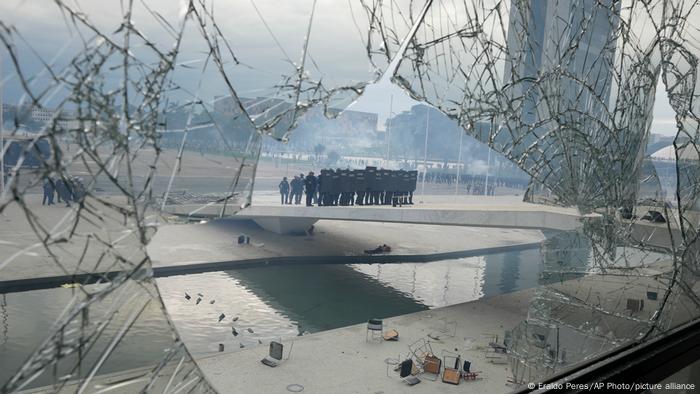 A través de una ventana destrozada se ve a la policía antidisturbios formando frente al Palacio de Planalto tras los manifestantes.