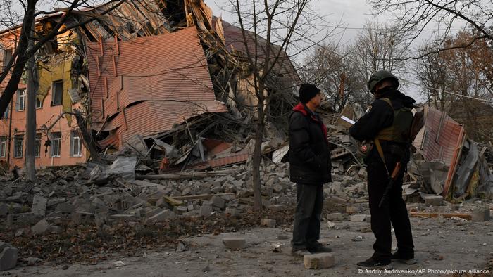 Ein Zivilist und ein uniformierter Mann stehen vor den Trümmern einer zerbombten Schule in Kramatorsk 
