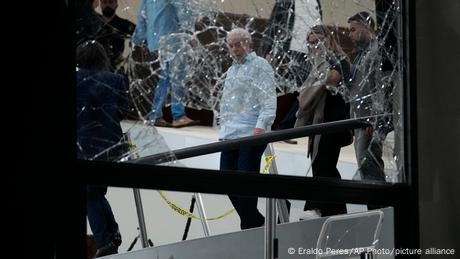 Brazil's president walks past a damaged window