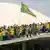 Multidão de verde e amarelo e com bandeira do Brasil diante da cúpula do Congresso Nacional