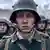 Still from the movie in which a young soldier looks sad, as other soldiers are around him