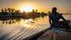 Un homme assis dans une pirogue observe le coucher du soleil
Un homme assis dans une pirogue observe le coucher du soleil