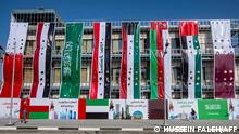 Banners showing the flags of (L to R) Bahrain, Yemen, Saudi Arabia, Iraq, Kuwait, Oman, the United Arab Emirates, and Qatar hang off a building under construction while below banners welcoming the national teams of said countries are displayed by a pavement as part of preparations ahead of the 25th Arabian Gulf Cup football championship in Iraq's southern city of Basra on December 29, 2022. (Photo by Hussein FALEH / AFP)