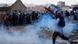 A protester is seen throwing something amid teargas smoke. A protester is seen throwing something amid teargas smoke.