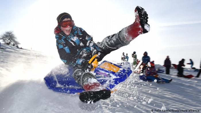 Grundschüler toben sich mit Snowboard im Schnee aus