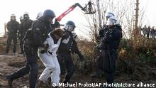 Police officers lead away a demonstrator the at village Luetzerath near Erkelenz, Germany, Tuesday, Jan. 10, 2023. The village of Luetzerath is occupied by climate activists fighting against the demolishing of the village to expand the Garzweiler lignite coal mine near the Dutch border. Poster read: „1,5 degrees celsius means: Luetzerath stays. (AP Photo/Michael Probst)