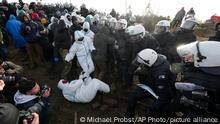 Police officers scuffle with demonstrators at the village of Luetzerath near Erkelenz, Germany, Tuesday, Jan. 10, 2023. The village of Luetzerath is occupied by climate activists fighting against the demolishing of the village to expand the Garzweiler lignite coal mine near the Dutch border. Poster read: „1,5 degrees celsius means: Luetzerath stays. (AP Photo/Michael Probst)