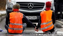Activists of Letzte Generation (Last Generation) who glued themselves to a street to protest for a speed limit on highways as well as for affordable public transport, hold hands as they sit on the tarmac, in Munich, Germany, December 14, 2022. REUTERS/Michaela Rehle