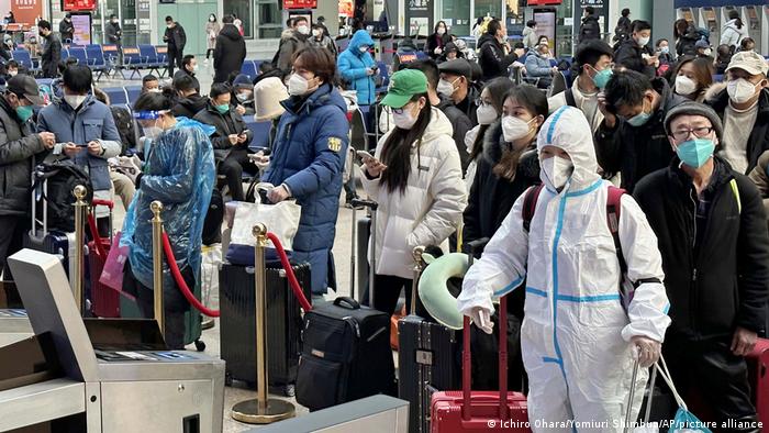 Un grupo de pasajeros chinos espera para abordar un tren en la estación de Pekín.