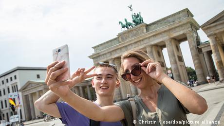 Ein Mann und eine Frau machen ein Selfie vorm Brandenburger Tor.