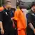 A Somali pirate, in orange shirt, is escorted by Malaysian police officers as he leaves Bukit Jalil Police Station in Kuala Lumpur