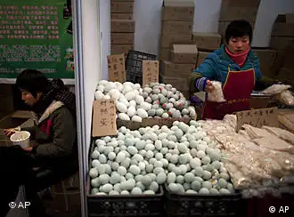 A vendor, left, eats her lunch while another vendor arranges food for sale at a market in Beijing, China, Friday, Jan. 7, 2011. Stabilizing price levels will receive more prominent status, the People's Bank of China said in a report after an annual planning meeting. (AP Photo/Alexander F. Yuan)