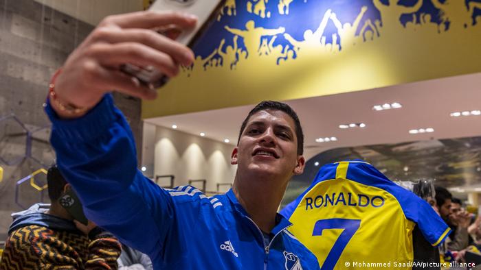 ein Al-Nassr-Fan macht im Fanshop ein Selfie vor Ronaldo-Trikot