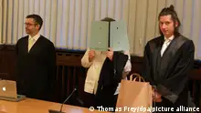 11.01.2023, Rheinland-Pfalz, Koblenz: Die 37 Jahre alte Angeklagte (M) steht im Gerichtssaal des Oberlandesgerichts zwischen ihren Anwälten. Ihr wird vorgeworfen, sie habe eine Jesidin als Sklavin gehalten und weitere Verbrechen begangen. Am Mittwoch hat der Prozess gegen die mutmaßliche IS-Anhängerin vor dem Oberlandesgericht Koblenz begonnen. (Zu dpa «Prozessauftakt gegen mutmaßliche IS-Anhängerin und Sklavenhalterin») Foto: Thomas Frey/dpa +++ dpa-Bildfunk +++