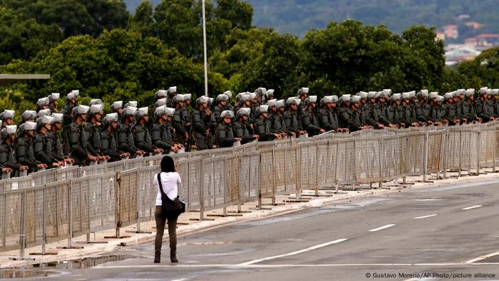 Foto de una persona que camina frente a agentes de seguridad en Brasil