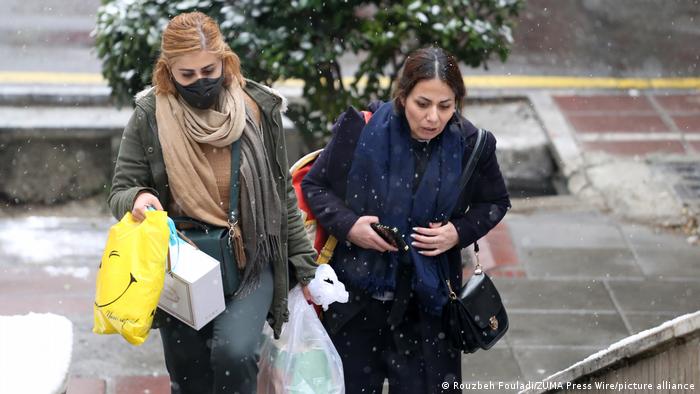 Zwei Iranerinnen (ohne Kopftuch) mit Einkäufen auf der winterlichen Straße in Teheran 