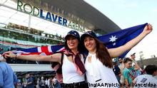 Dos aficionadas sostienen sonrientes la bandera australiana en el Rod Laver Arena.