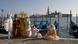 Figures in traditional costumes stand by the water's edge in Venice. Figures in traditional costumes stand by the water's edge in Venice.