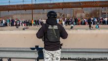 CIUDAD JUAREZ, MEXICO - DECEMBER 21: A Mexican National Guardsman observes as migrants line up along the U.S.-Mexico border fence to apply for asylum in the United States on December 21, 2022 as viewed from Ciudad Juarez, Mexico. Texas Governor Greg Abbott ordered 400 troops to the U.S.-Mexico border in El Paso, which is under a state of emergency due to a surge of migrants crossing from Mexico into the city. Border officials expect an even larger migrant surge at the border if the pandemic era Title 42 regulation is lifted. John Moore/Getty Images/AFP (Photo by JOHN MOORE / GETTY IMAGES NORTH AMERICA / Getty Images via AFP)