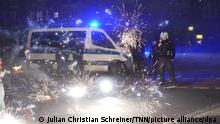 Polizeibeamte stehen hinter explodierendem Feuerwerk. (Zu dpa Silvester-Krawalle: Vor allem Ältere halten hohe Strafen für richtig) +++ dpa-Bildfunk +++