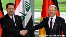 German Chancellor Olaf Scholz (R) and Iraq's Prime Minister Mohammed Shia al-Sudani shake hands at the end of a joint press conference following talks at the Chancellery in Berlin on January 13, 2023. (Photo by Tobias SCHWARZ / AFP)