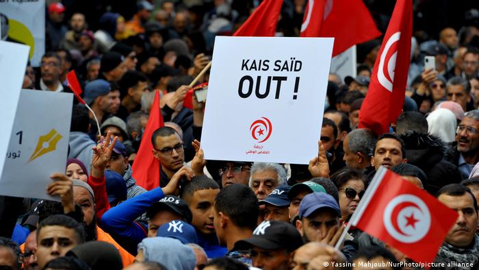 Demonstranten mit Tunesien-Fähnchen und einem Plakat Kais Saied - out!