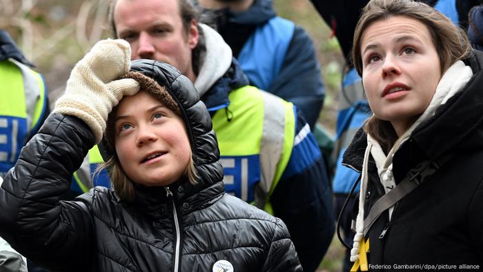 Luisa Neubauer blickt ,rechts stehend, nach oben, links von ihr steht die bekannte schwedische Klimaaktivistin Greta Thunberg, die sich mit der rechten Hand an den Kopf fasst. .