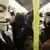 People in Guy Fawkes masks on a train